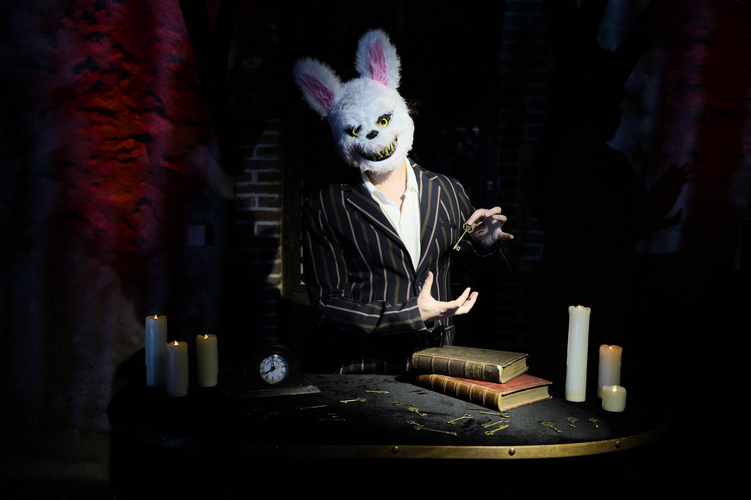 Comédien costumé en maître des énigmes horreur posant un défi logique aux invités d'une soirée.